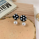 Mismatched drop earrings with black and white polka dots and a pearl accent, adding a playful touch to any outfit.